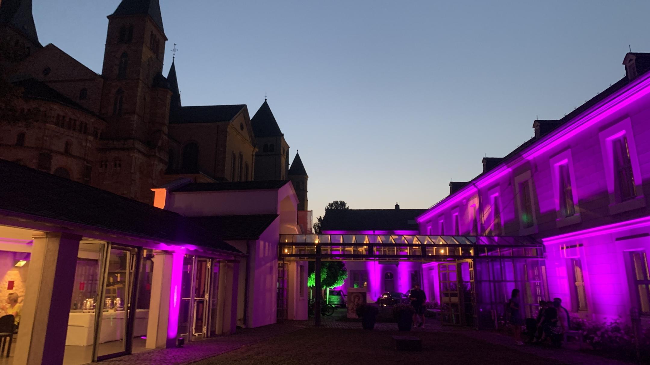 Das Museum am Dom Trier ist für die Museumsnacht von außen in Farben wie Pink und Gelb beleuchtet.