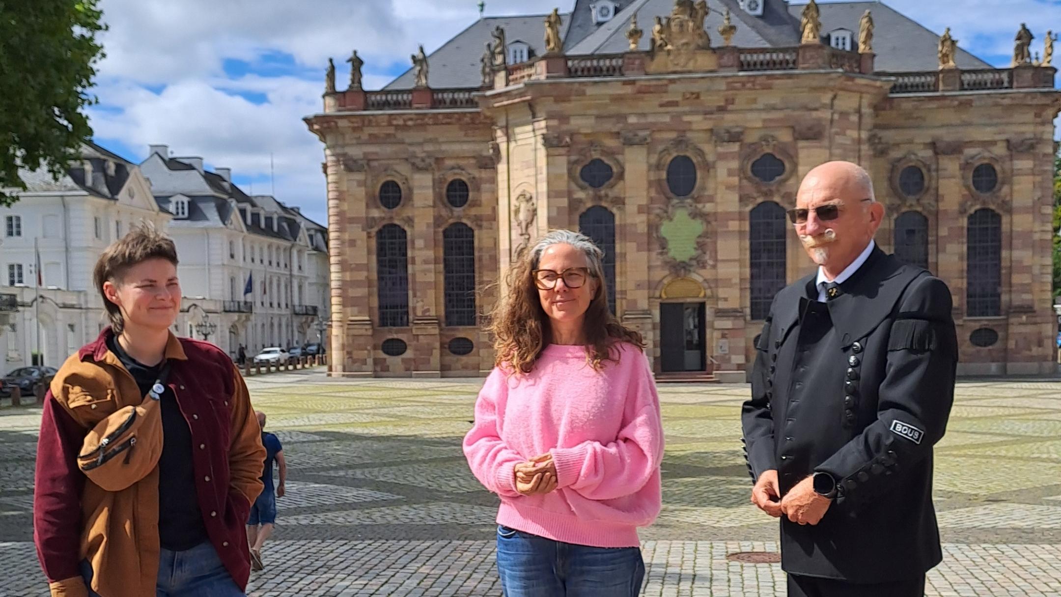 Drei Personen stehen vor einer Kirche.