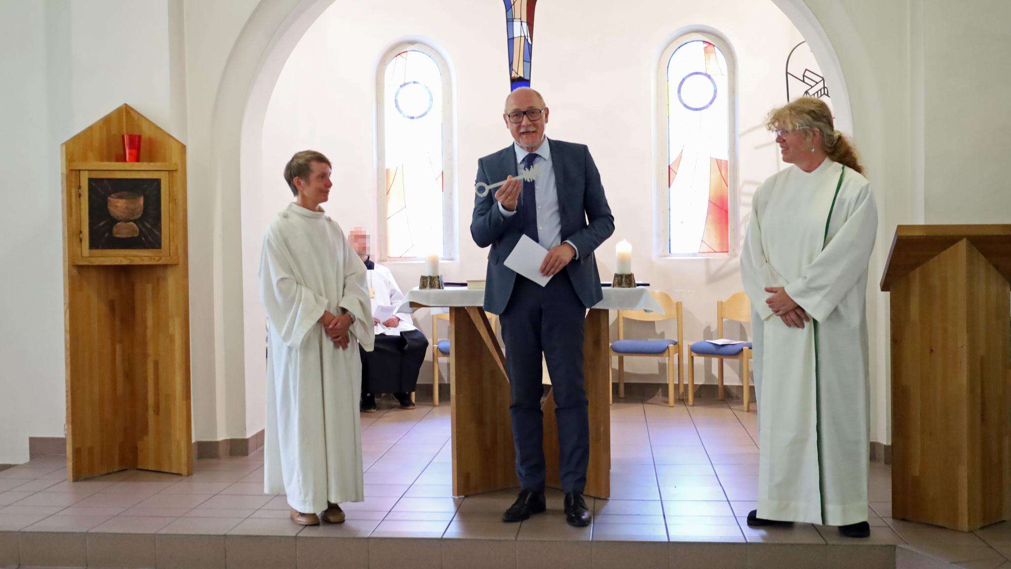 Der Leiter der Abteilung Seelsorge und Lebenswelten im Bischöflichen Generalvikariat Ulrich Stinner (Mitte) übergibt symbolisch den Schlüssel von Carmen Folz (links) an Marion Bexten (rechts).