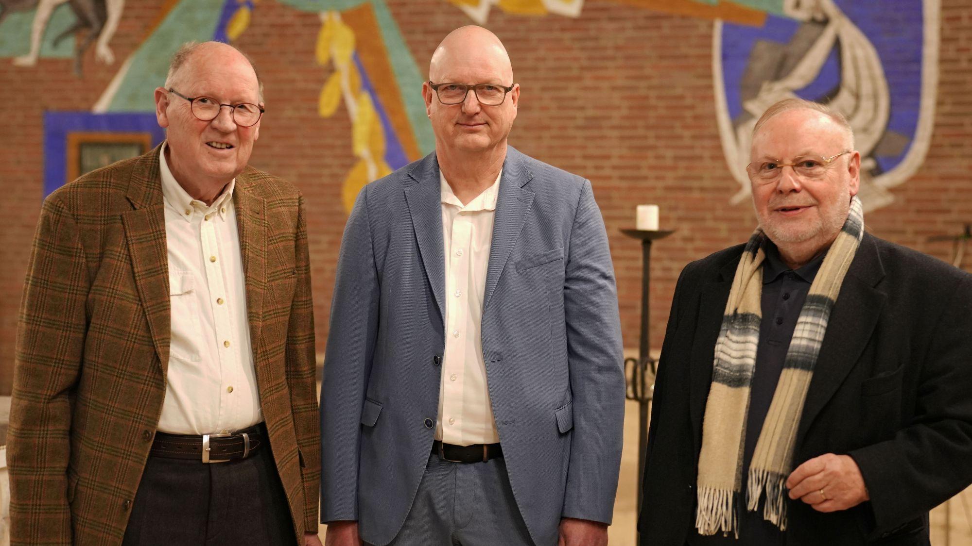 Drei Männer blicken lächelnd in die Kamera