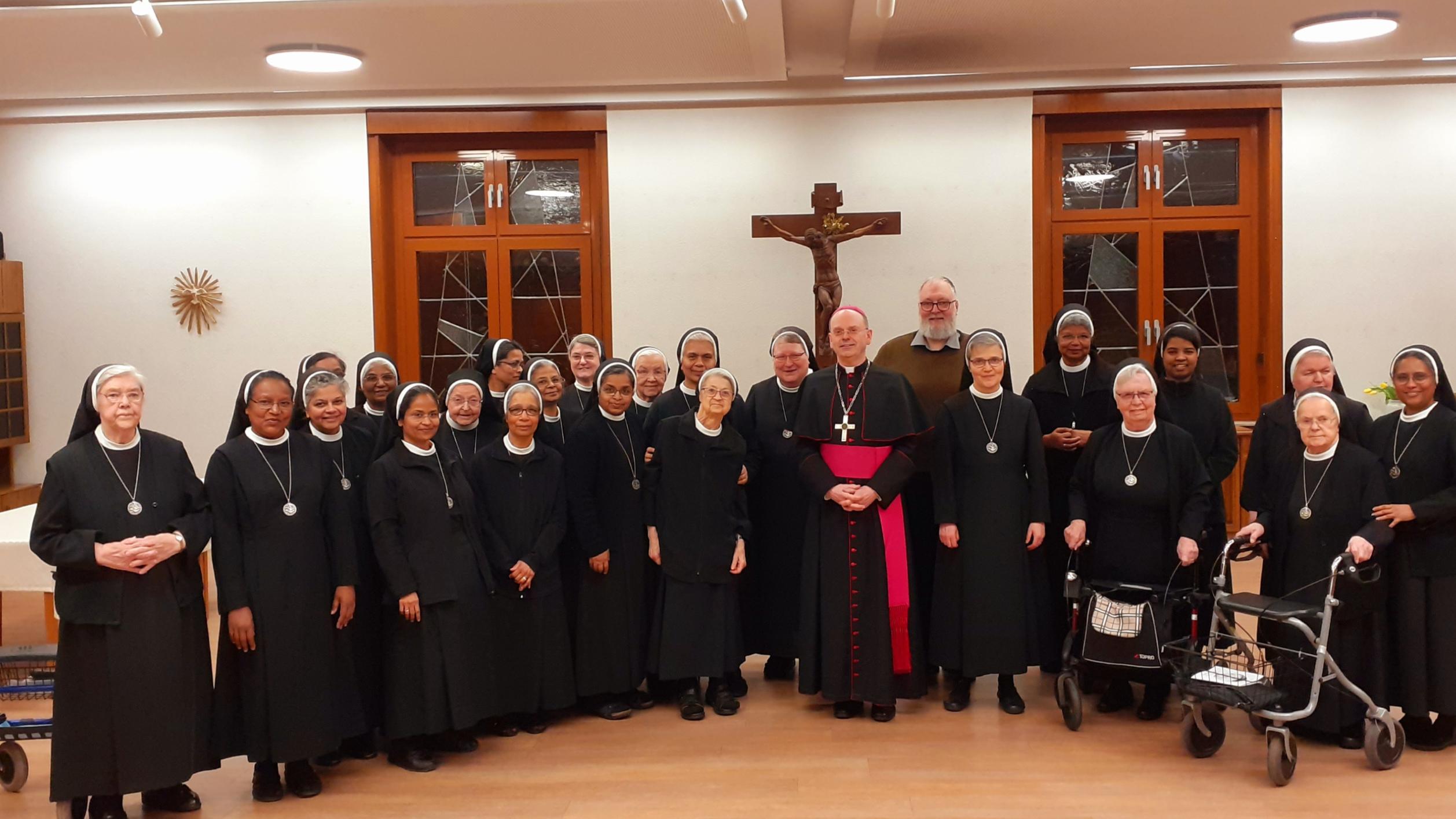 Viele Ordensschwestern stehen um Weihbischof Brahm lächelnd für ein Gruppenfoto zusammen.