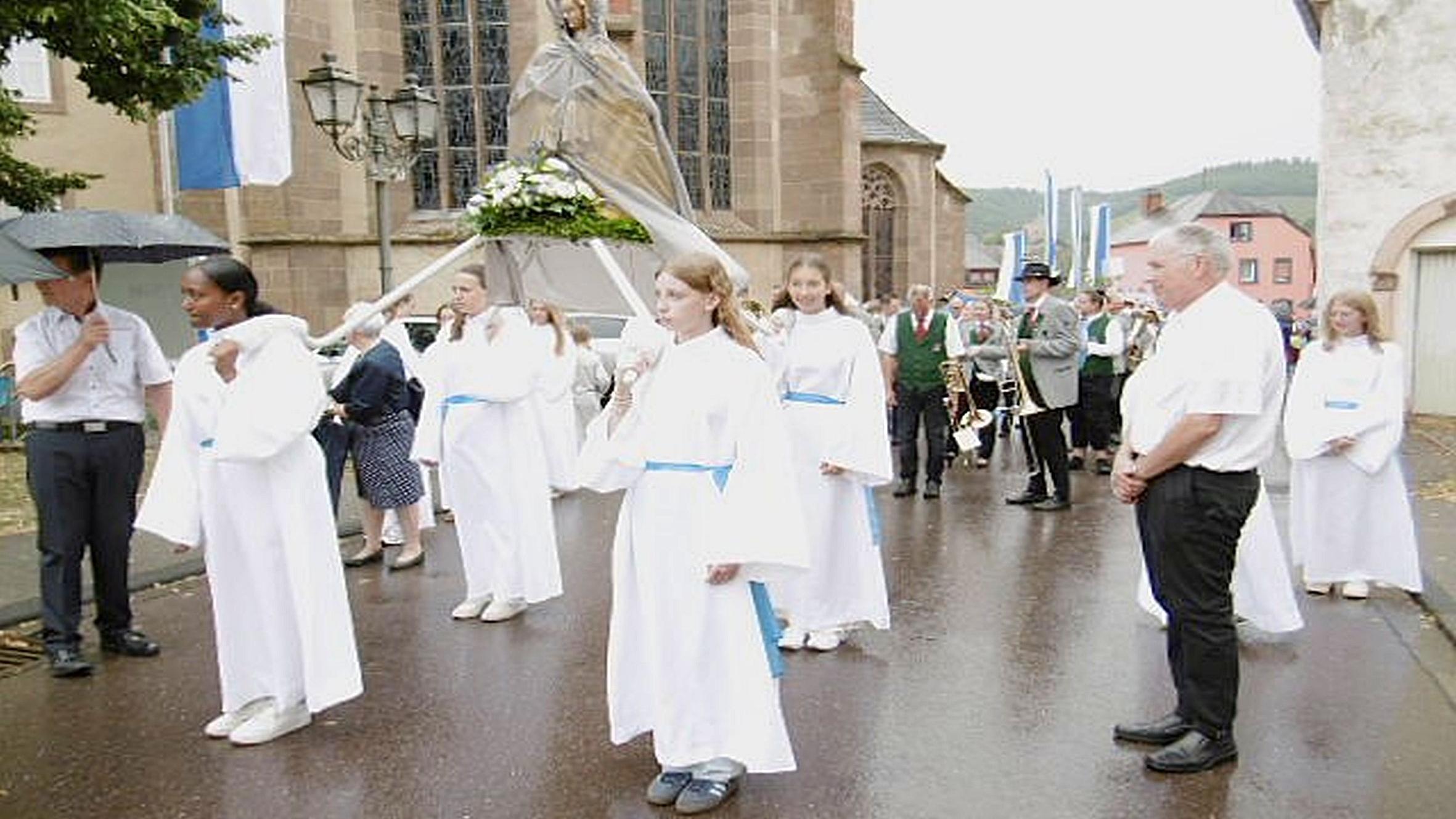 Weiß gekleidete Mädchen tragen eine Marienfigur