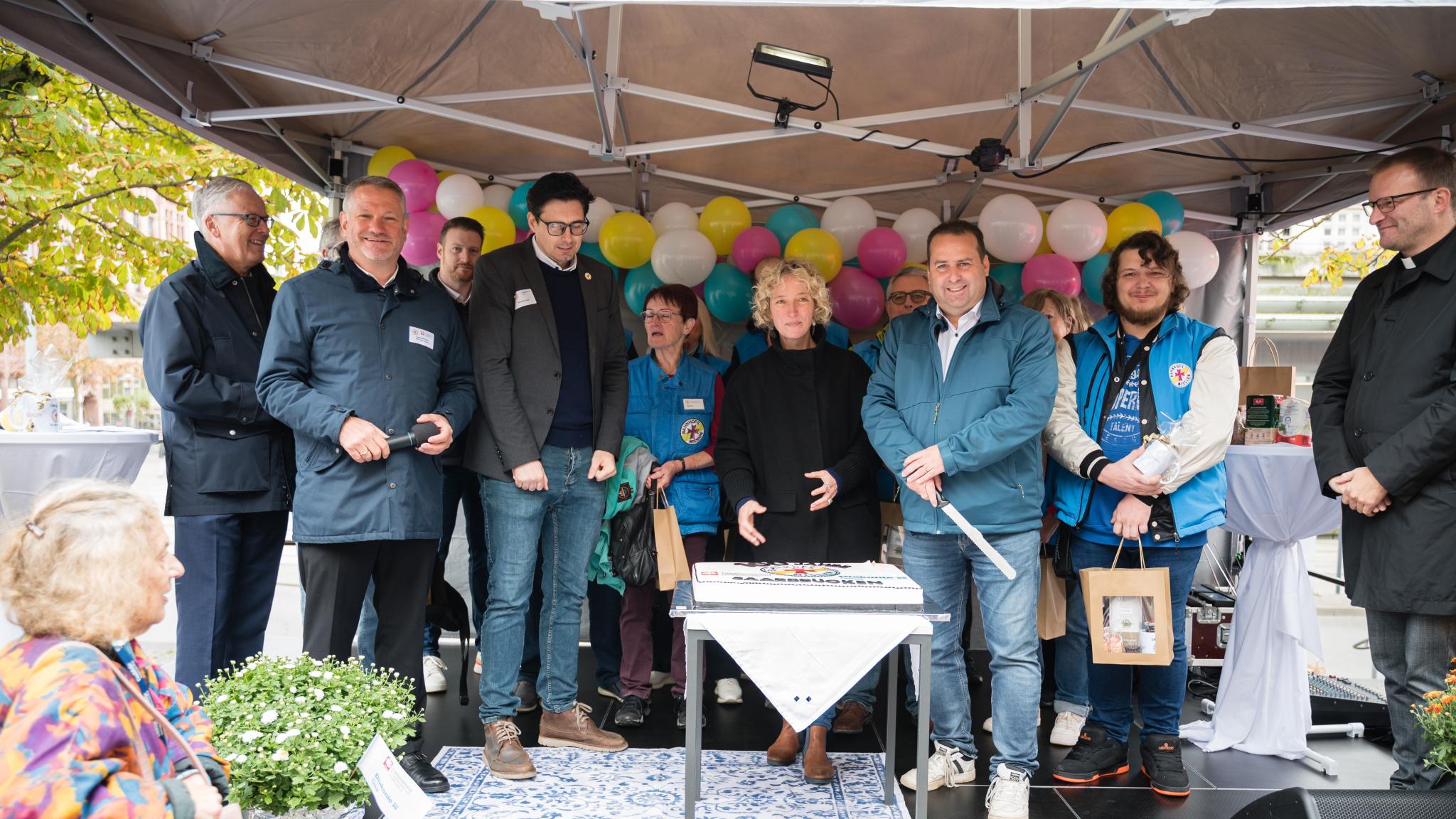 Sozialminister Dr. Magnus Jung (3.v.r.) schnitt mit Jennifer Sauer, Leiterin Bahnhofsmanagement (Mitte), und Tafelkoordinator Thorsten Junk (4.v.l.) die Torte an. Es feierten mit (v.l.n.r.): Dr. Klaus Vornhusen (Deutsche Bahn), Caritasdirektor Michael Schley und Tobias Raab sowie viele Ehrenamtliche.