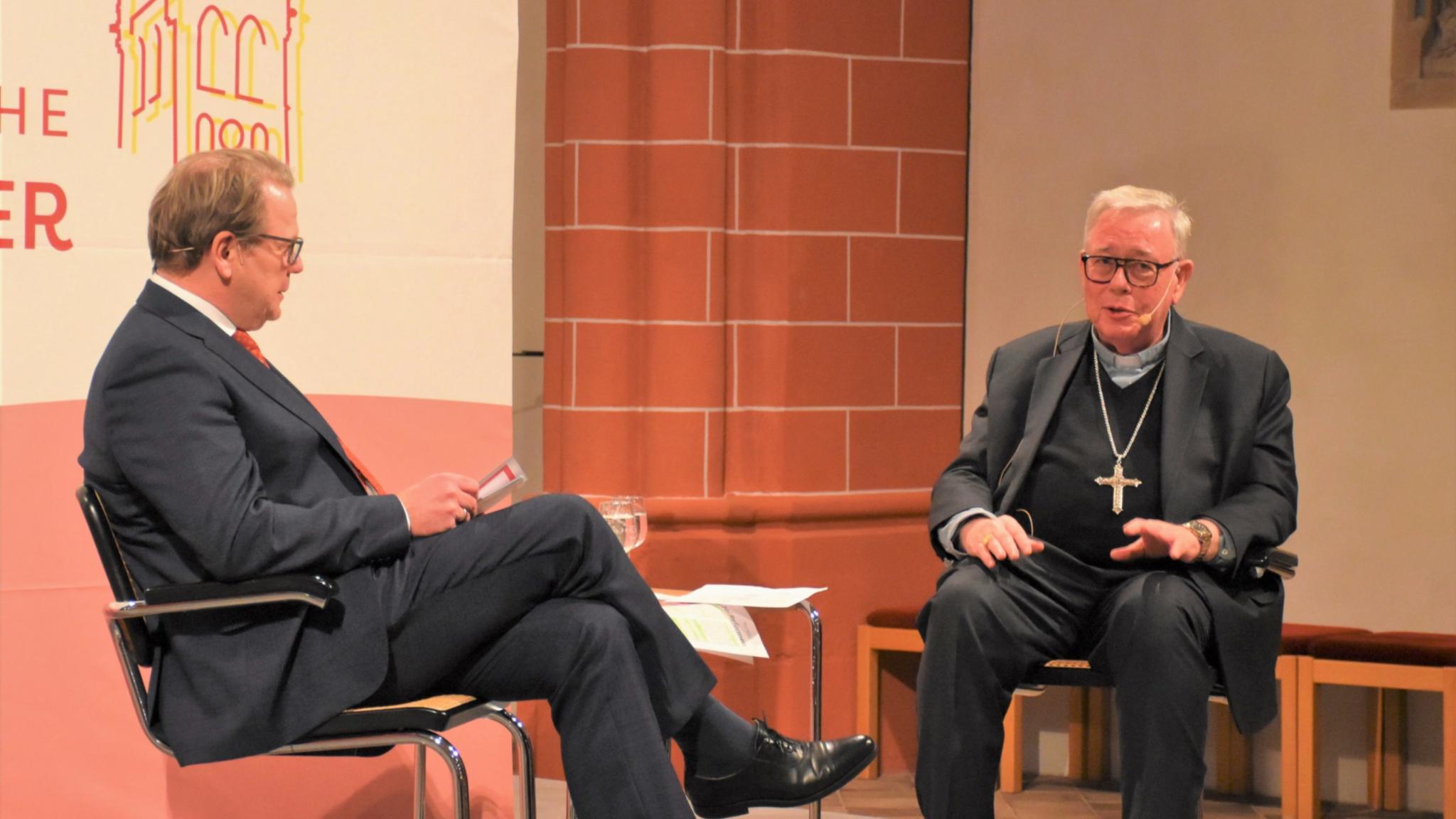 Zwei Männer unterhalten sich sitzend auf einer Bühne