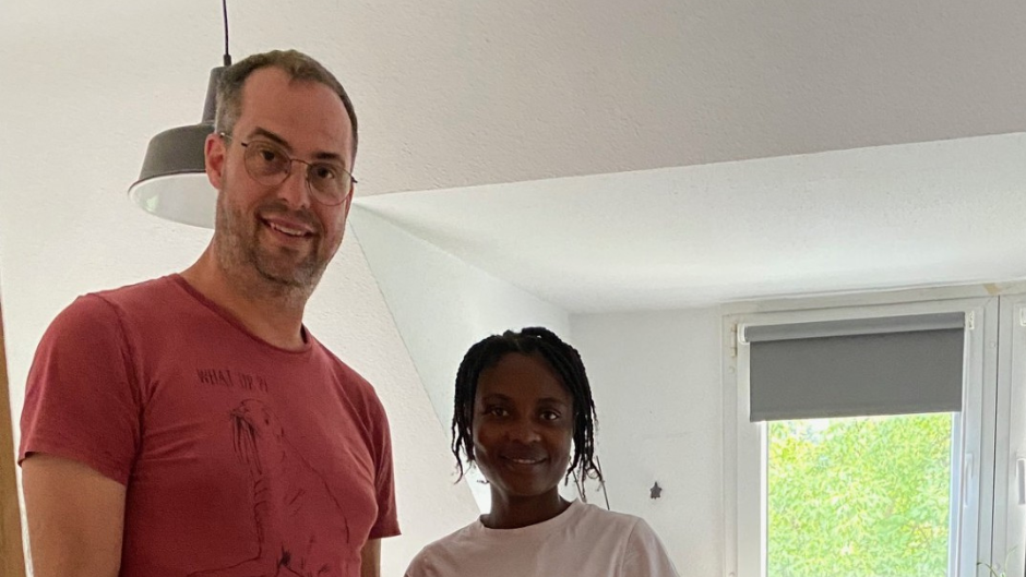 Ein Mann in rotem T-Shirt steht neben einer Frau. Beide lächeln.