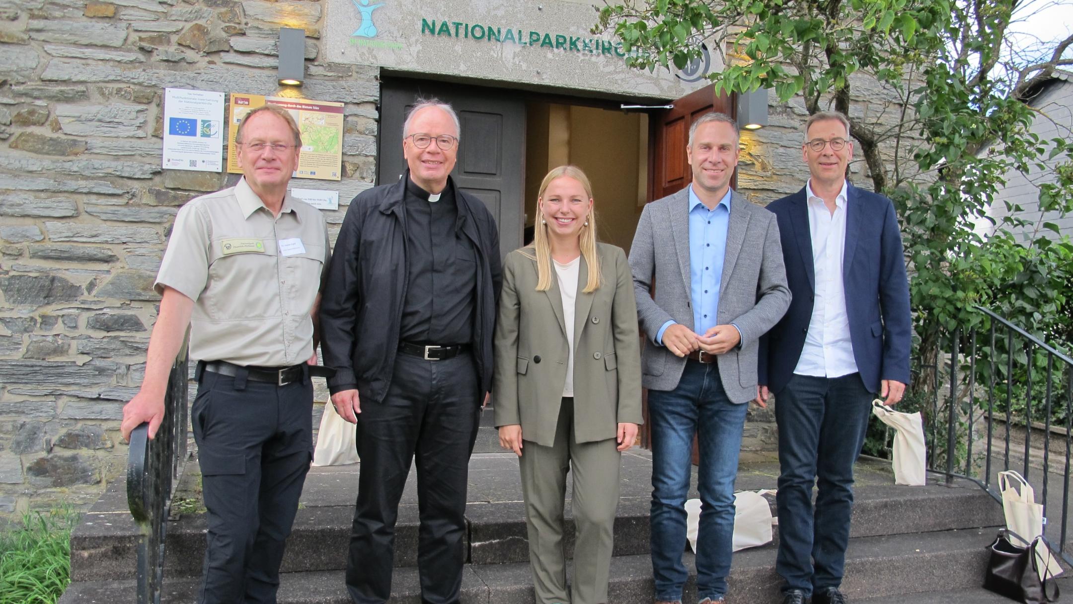 Dr. Harald Egidi, Bischof Dr. Stephan Ackermann, Kira Braun, Nico Steinbach und Superintendent Dr. Jörg Weber stehen vor dem Eingang zur Kirche von Muhl
