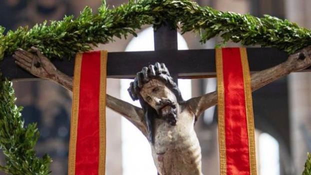 Jesus hängt am Kreuz, umrahmt von Palmzweigen