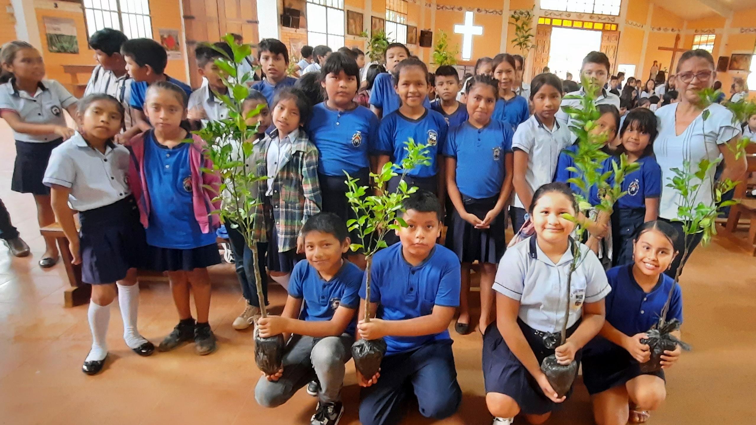 Ein Gruppenfoto einer Gruppe von Kindern mit Baumsetzlingen in einer Kirche in Bolivien, welche danach bei einer Aktion gepflanzt wurden.