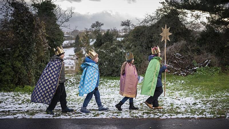 Vier verkleidete Sternsinger, die durch die Straßen ziehen