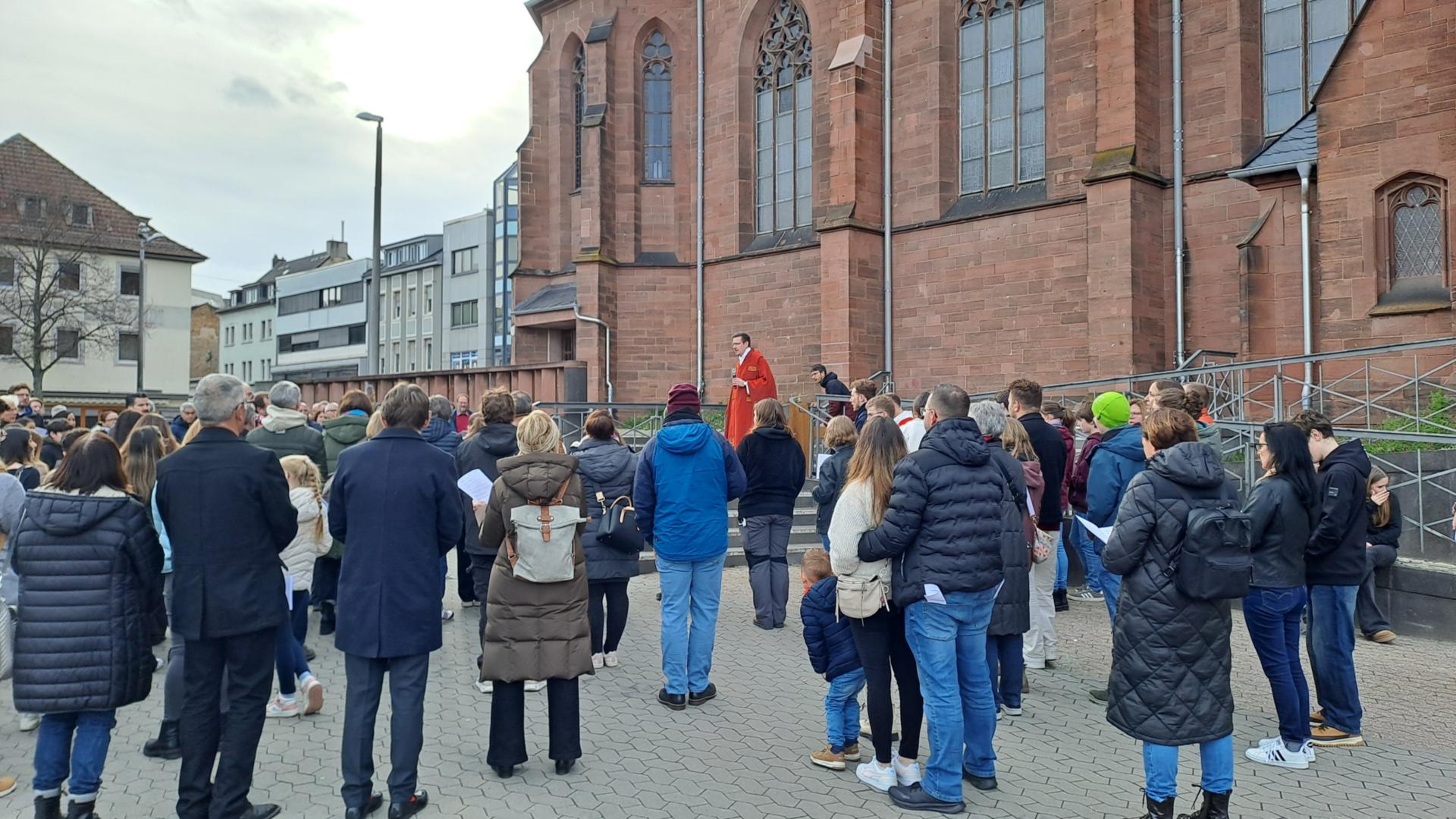 Eine Gruppe von Menschen steht auf dem Platz vor einer Kirche